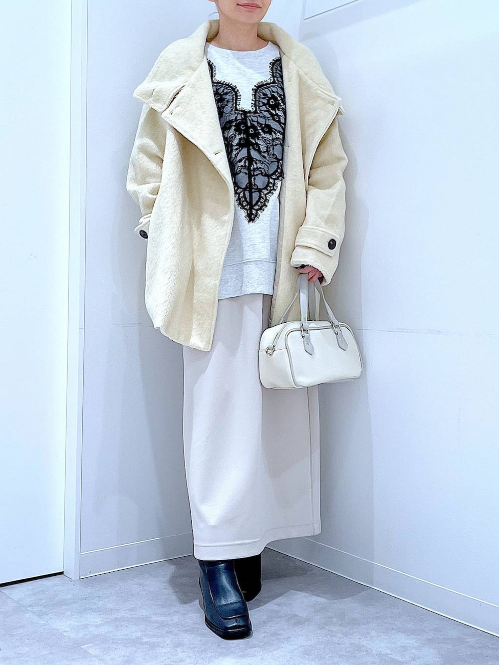 ベージュ系のスカート、ベージュ系のステンカラーコート、ブラック系のブーツを着用したレディースの冬コーディネートの6枚目の写真