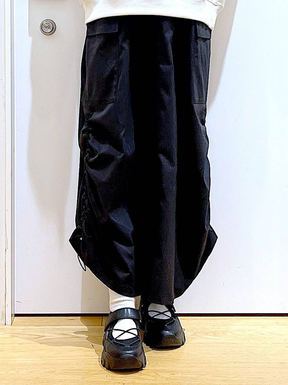 ブラック系のスニーカー、ブラック系のジャンパースカート、ブラック系のトートバッグを着用したレディースの冬コーディネートの8枚目の写真