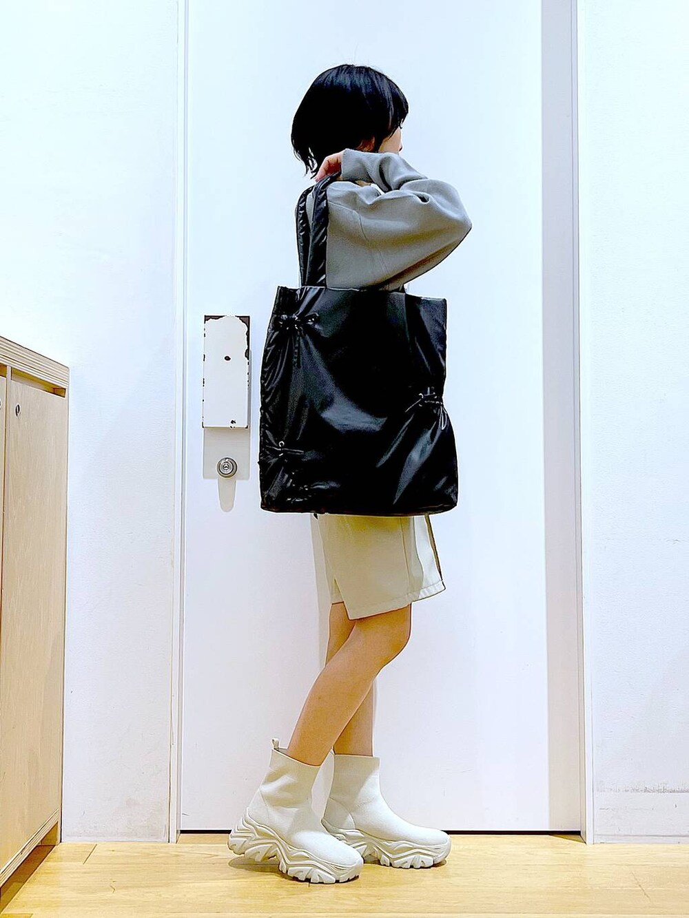 グレー系のニット/セーター、ブラック系のトートバッグ、ベージュ系のブーツを着用したレディースの冬コーディネートの4枚目の写真