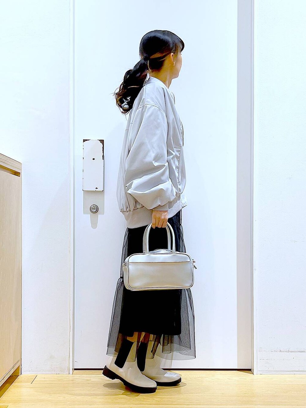 シルバー系のショルダーバッグ、グレー系のMA-1、ベージュ系のブーツを着用したレディースの春コーディネートの4枚目の写真