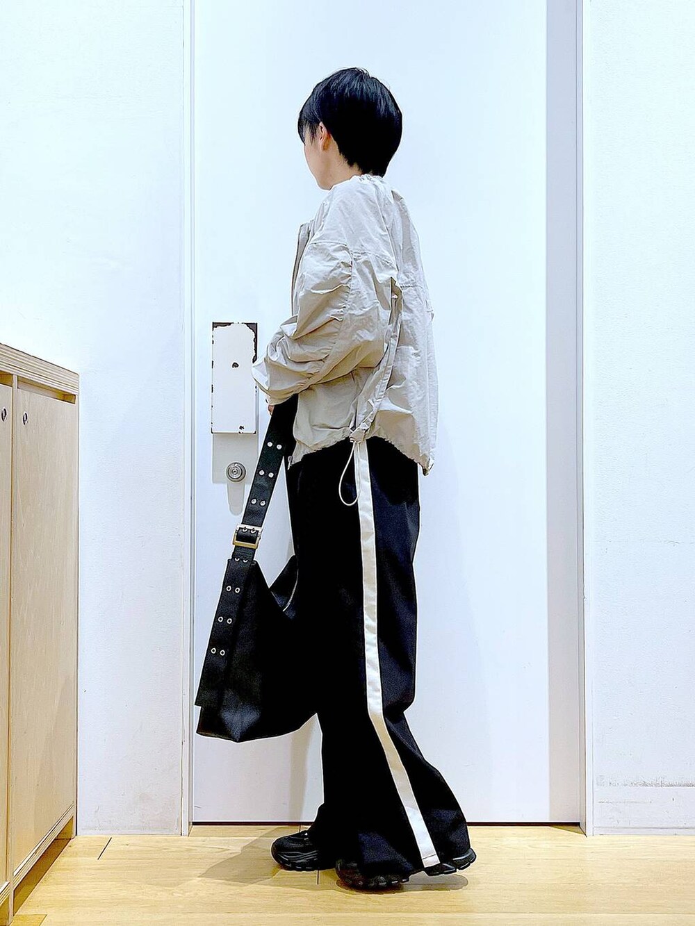 ブラック系のスラックス、ブラック系のスニーカー、ブラック系のショルダーバッグを着用したレディースの春コーディネートの3枚目の写真