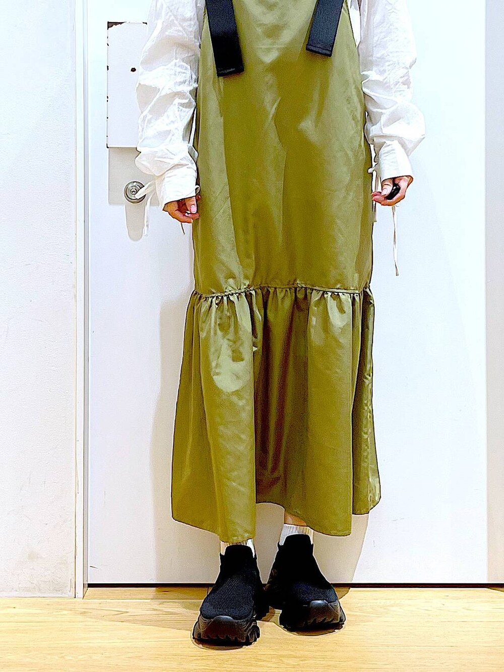 ブラック系のショルダーバッグ、グリーン系のワンピース、ホワイト系のシャツ/ブラウスを着用したレディースの春コーディネートの8枚目の写真