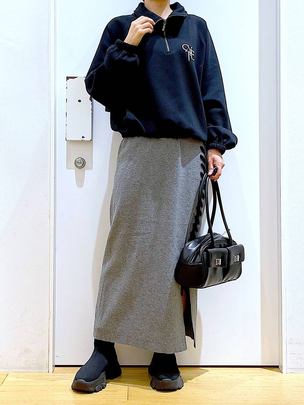 ブラック系のハンドバッグ、ブラック系のブーツ、グレー系のスカートを着用したレディースの冬コーディネートの6枚目の写真