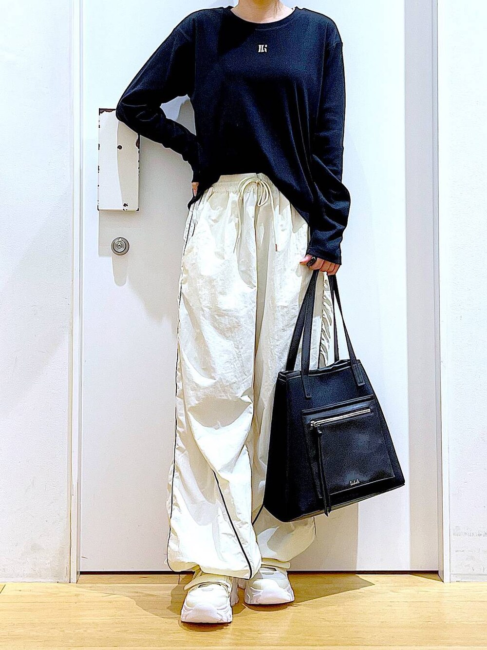 ホワイト系のスニーカー、ベージュ系のその他パンツ、ブラック系のトートバッグを着用したレディースの秋コーディネートの6枚目の写真