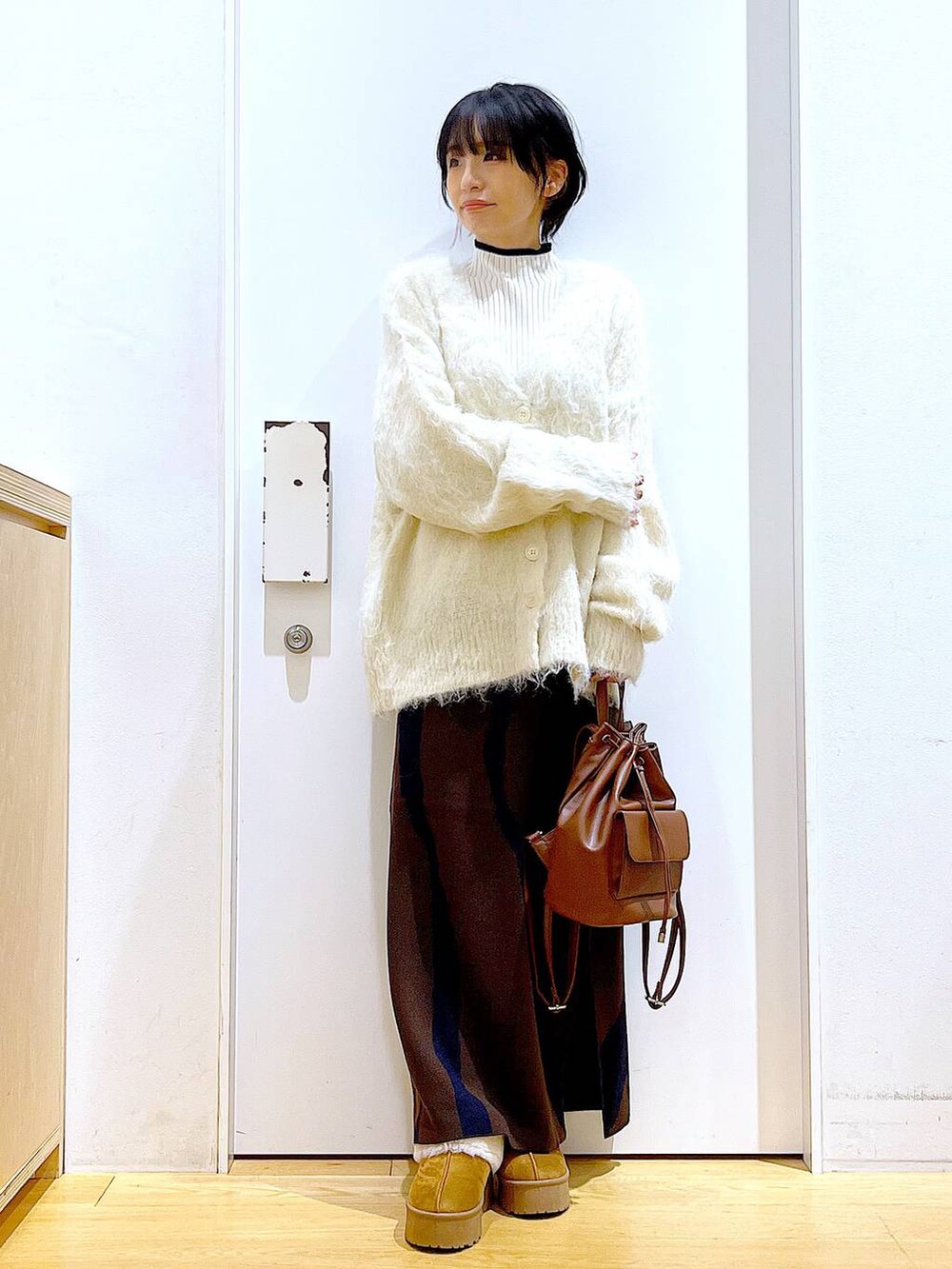 ベージュ系のニット/セーター、ブラウン系のバックパック/リュック、ブラウン系のスカートを着用したレディースの冬コーディネートの2枚目の写真