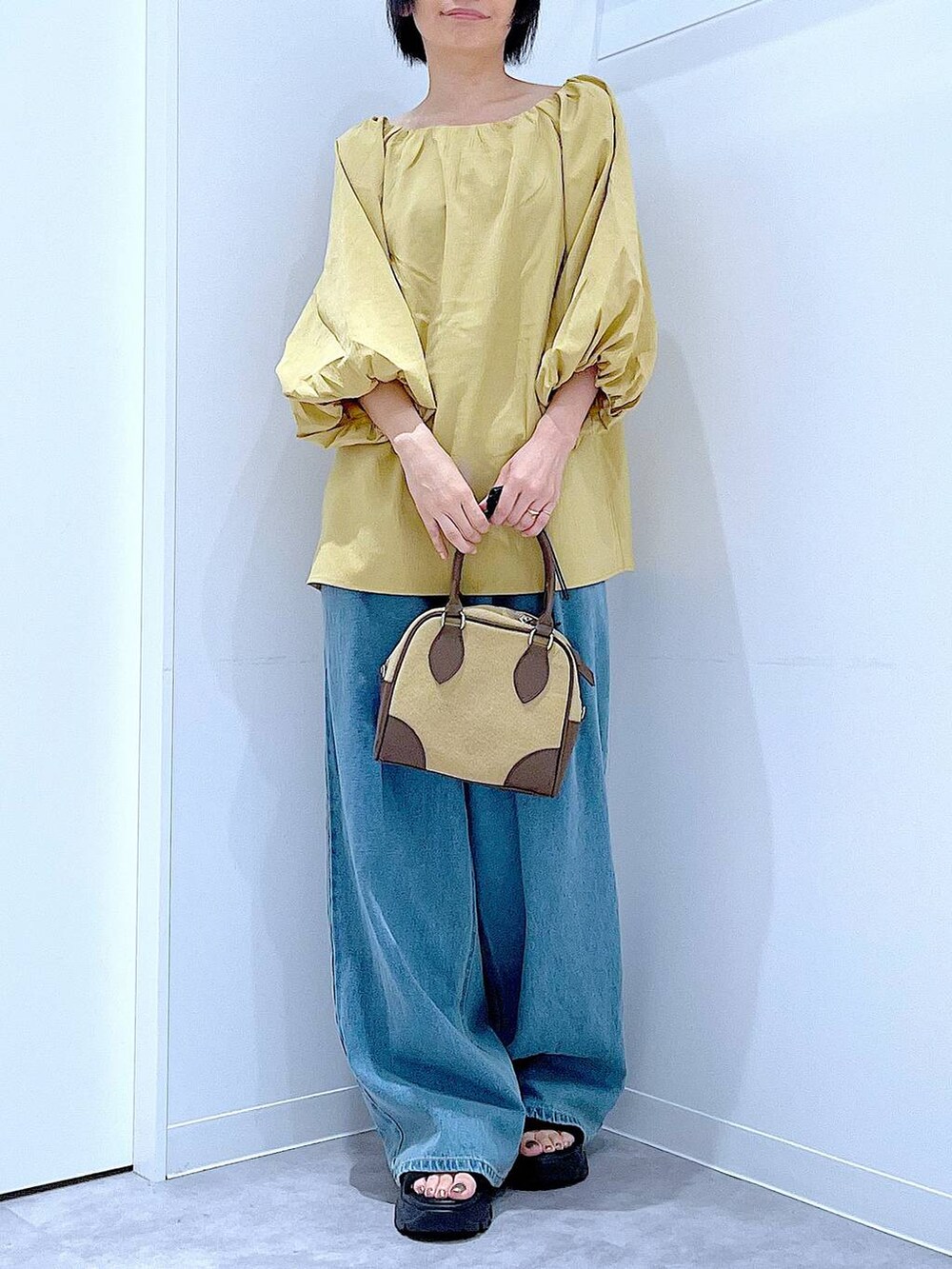 ブラック系のスニーカー、ブルー系のデニムパンツ、イエロー系のシャツ/ブラウスを着用したレディースの秋コーディネートの6枚目の写真