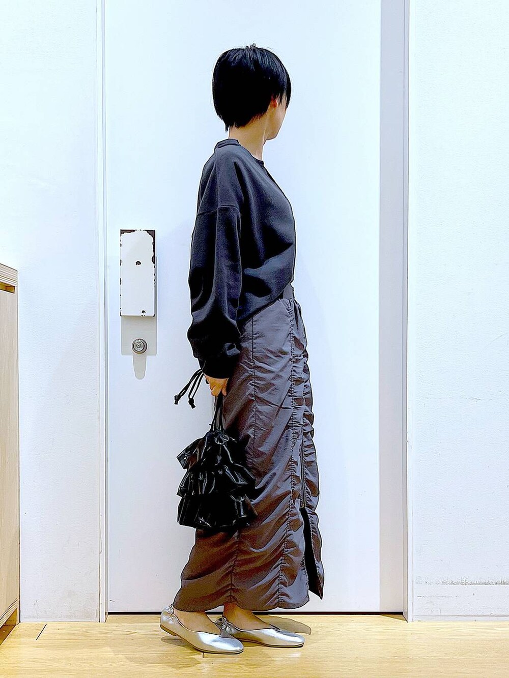 グレー系のスカート、ブラック系のショルダーバッグ、シルバー系のパンプスを着用したレディースの春コーディネートの4枚目の写真