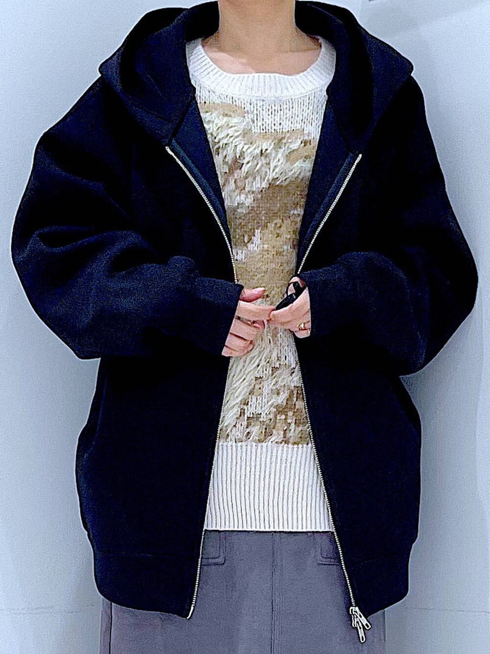 ホワイト系のハンドバッグ、ブラック系のブーツ、グレー系のスカートを着用したレディースの冬コーディネートの7枚目の写真