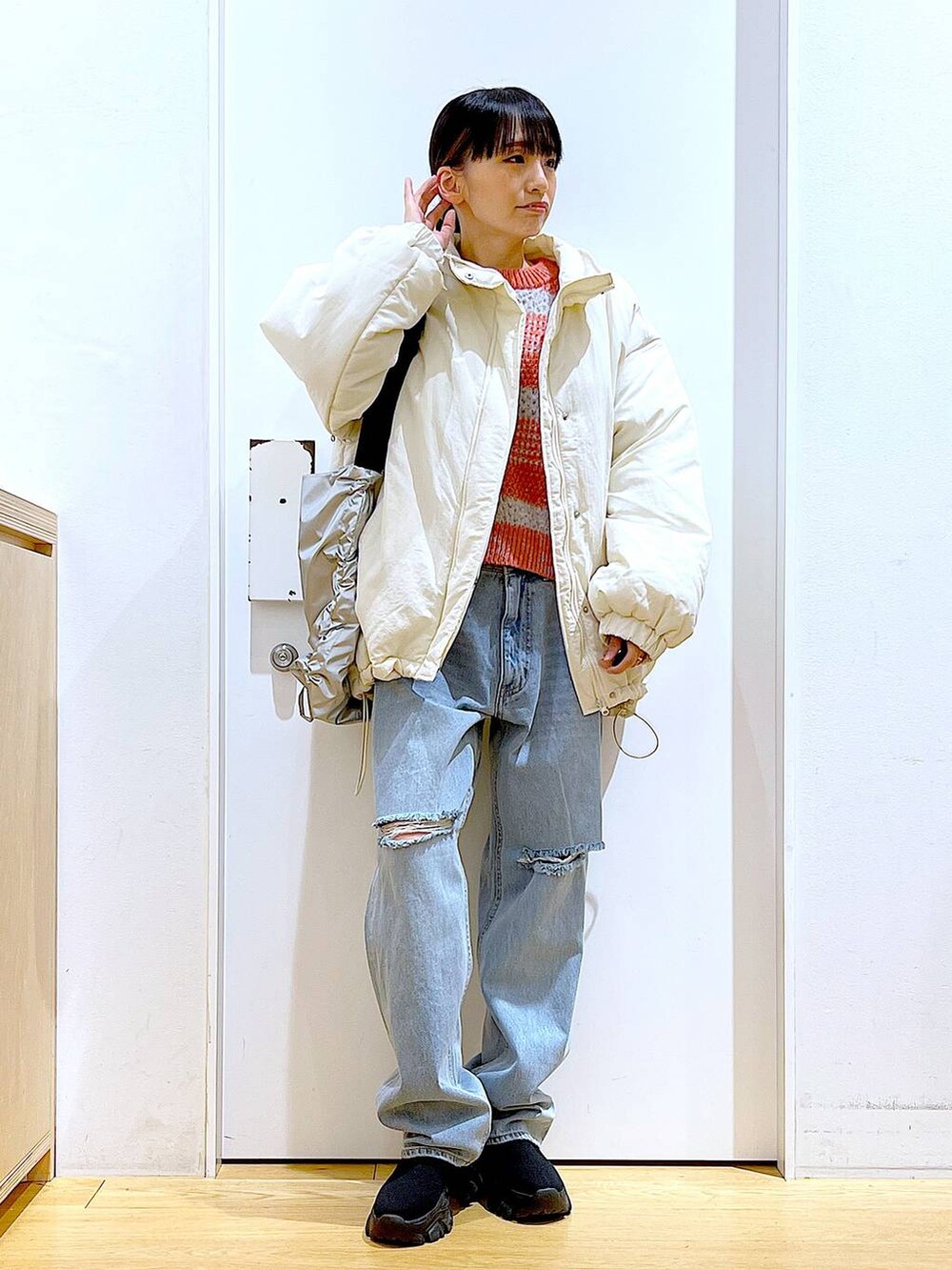 ブラック系のブーツ、ブルー系のデニムパンツ、シルバー系のショルダーバッグを着用したレディースの冬コーディネートの2枚目の写真