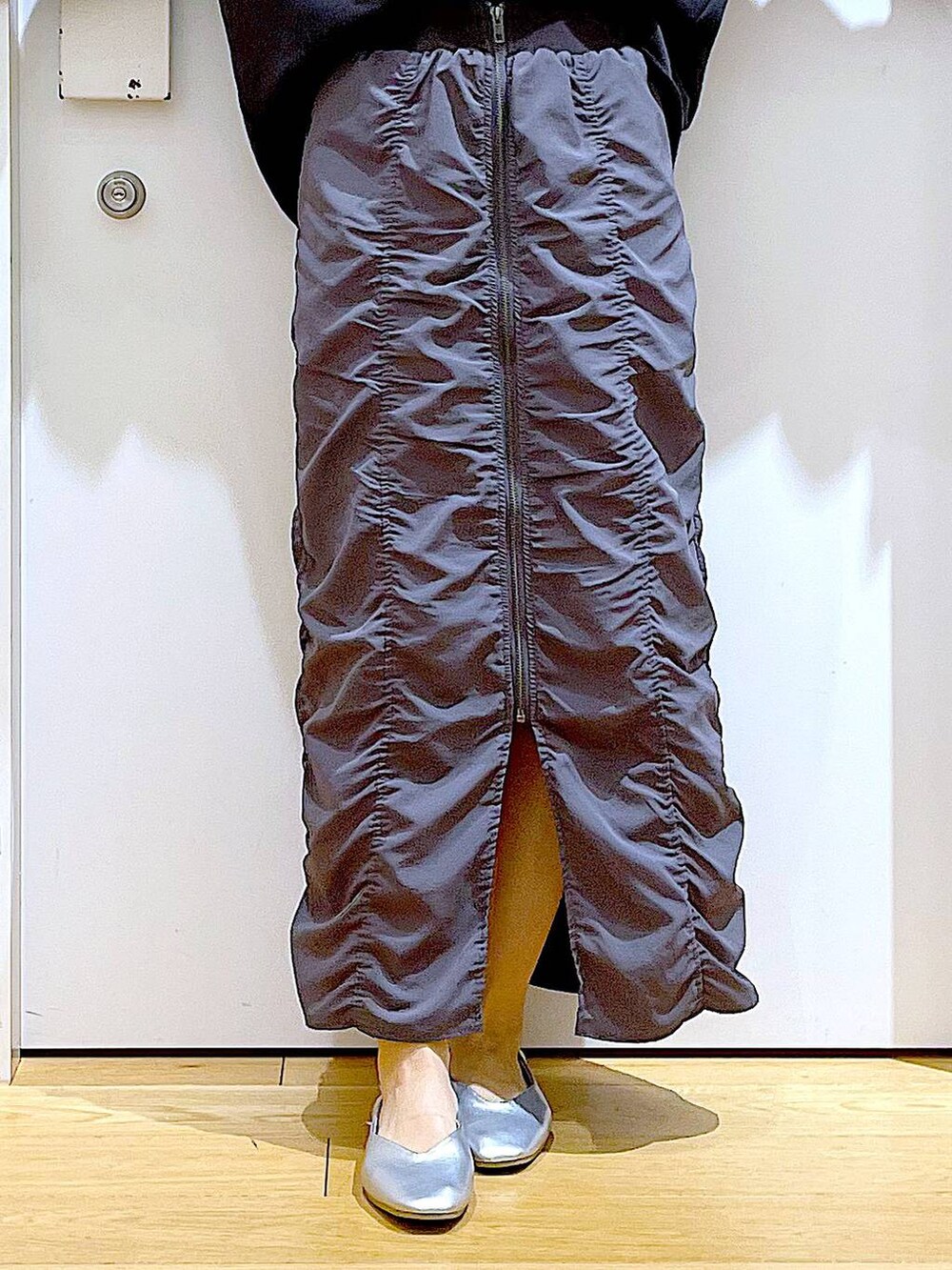 グレー系のスカート、ブラック系のショルダーバッグ、シルバー系のパンプスを着用したレディースの春コーディネートの8枚目の写真