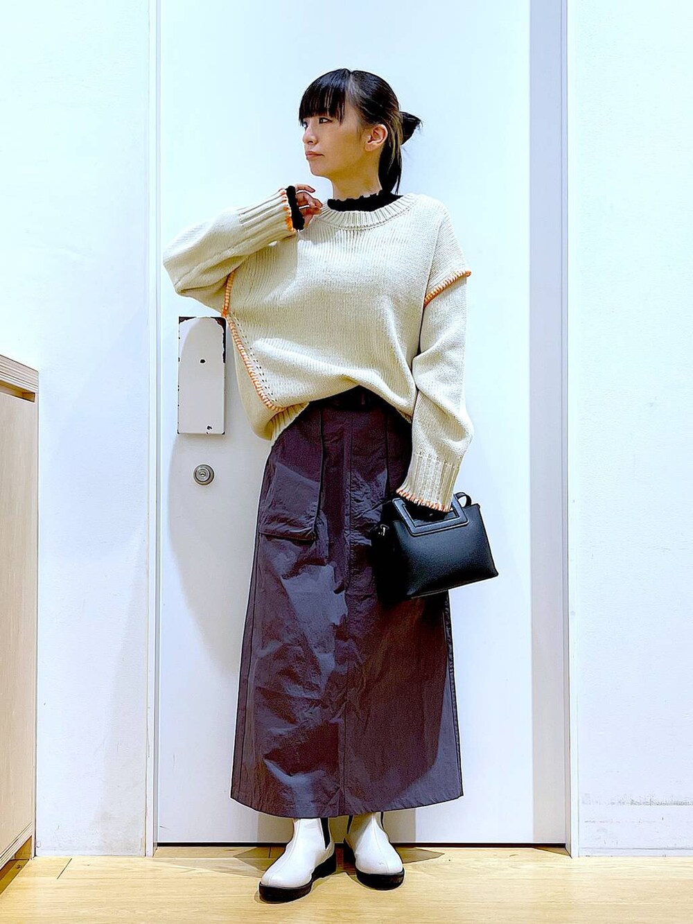 ブラック系のTシャツ/カットソー、ベージュ系のブーツ、ブラック系のショルダーバッグを着用したレディースの冬コーディネートの2枚目の写真