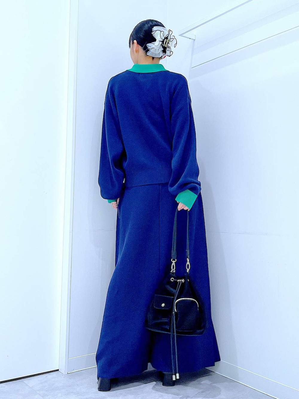 ブラック系のショルダーバッグ、ブラック系のブーツ、ブルー系のスカートを着用したレディースの冬コーディネートの5枚目の写真