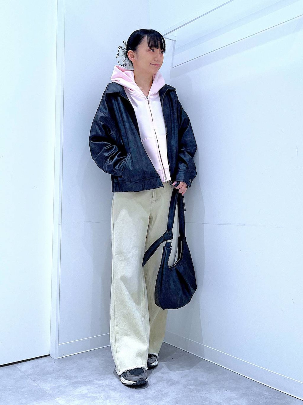 ブラック系のブルゾン、ベージュ系のデニムパンツ、ピンク系のパーカーを着用したレディースの冬コーディネートの2枚目の写真