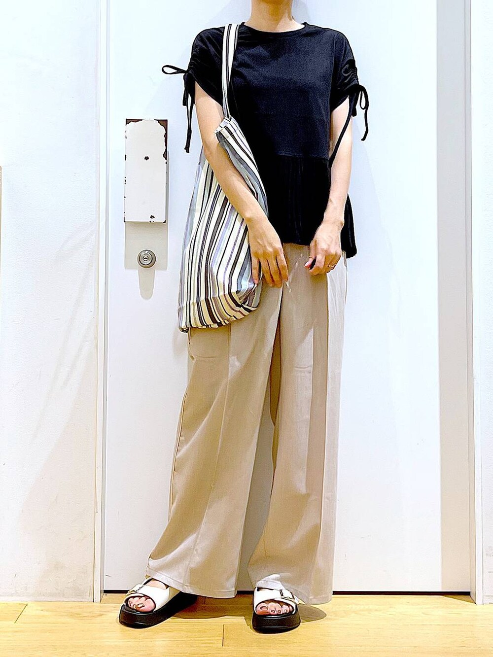 ホワイト系のサンダル、グリーン系のトートバッグ、ベージュ系のスラックスを着用したレディースの秋コーディネートの6枚目の写真