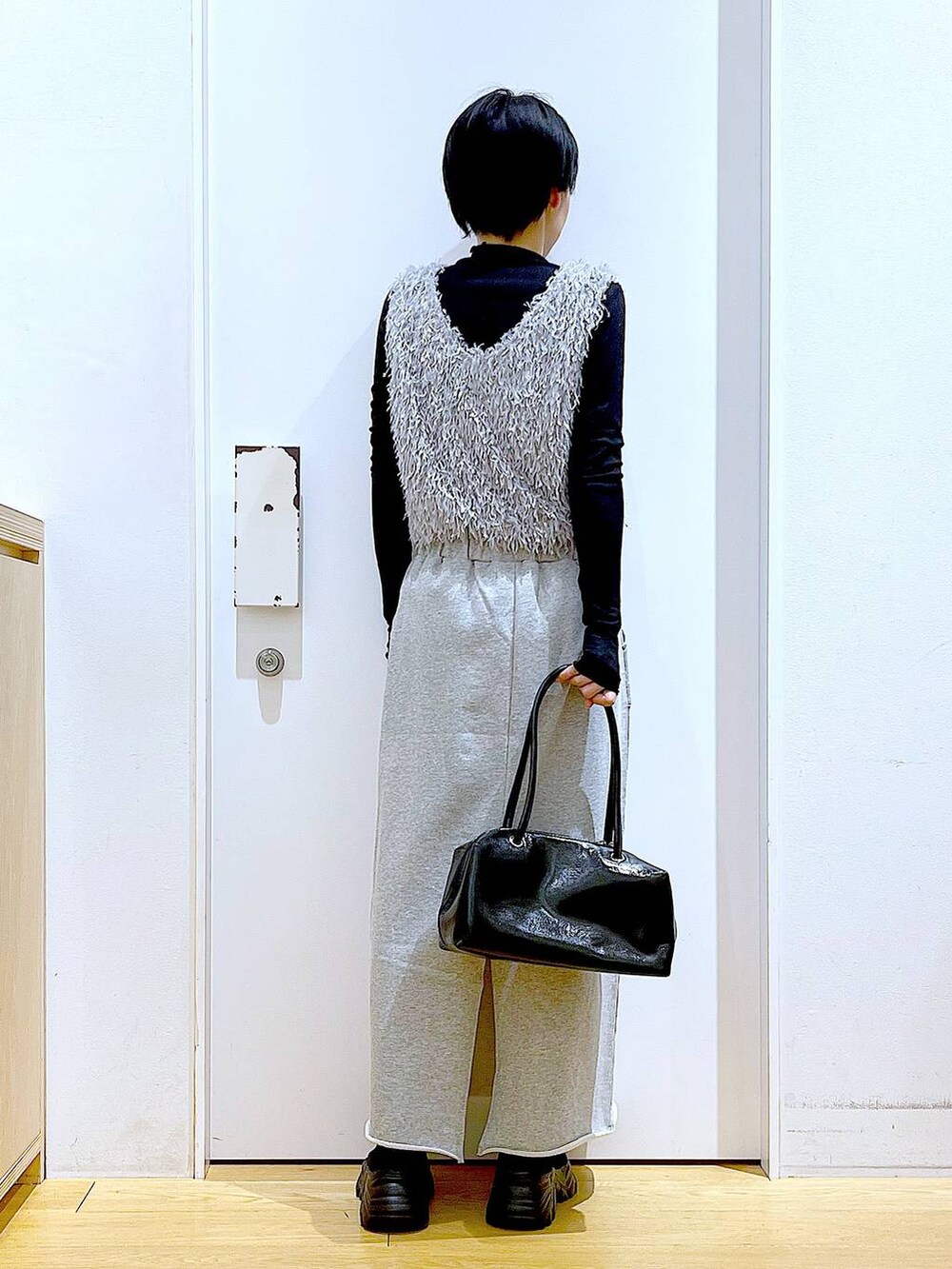 ブラック系のブーツ、ブラック系のTシャツ/カットソー、グレー系のスカートを着用したレディースの春コーディネートの5枚目の写真