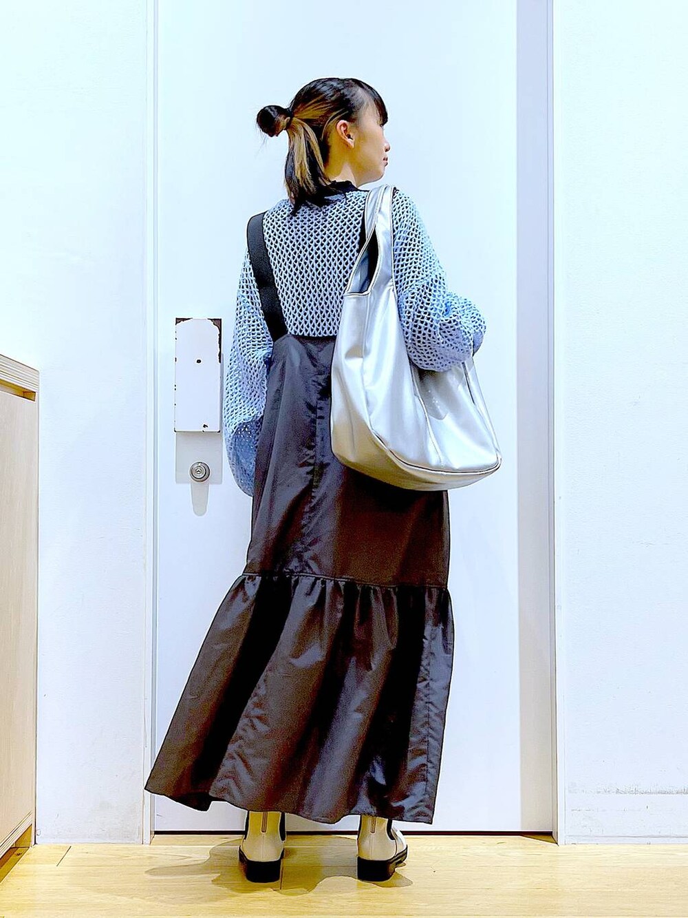 ブラック系のTシャツ/カットソー、ブルー系のニット/セーター、シルバー系のトートバッグを着用したレディースの春コーディネートの5枚目の写真