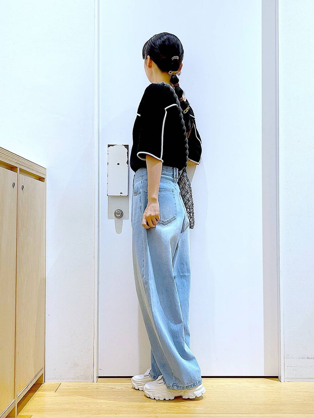 ホワイト系のスニーカー、ブルー系のデニムパンツ、グレー系のショルダーバッグを着用したレディースの夏コーディネートの3枚目の写真