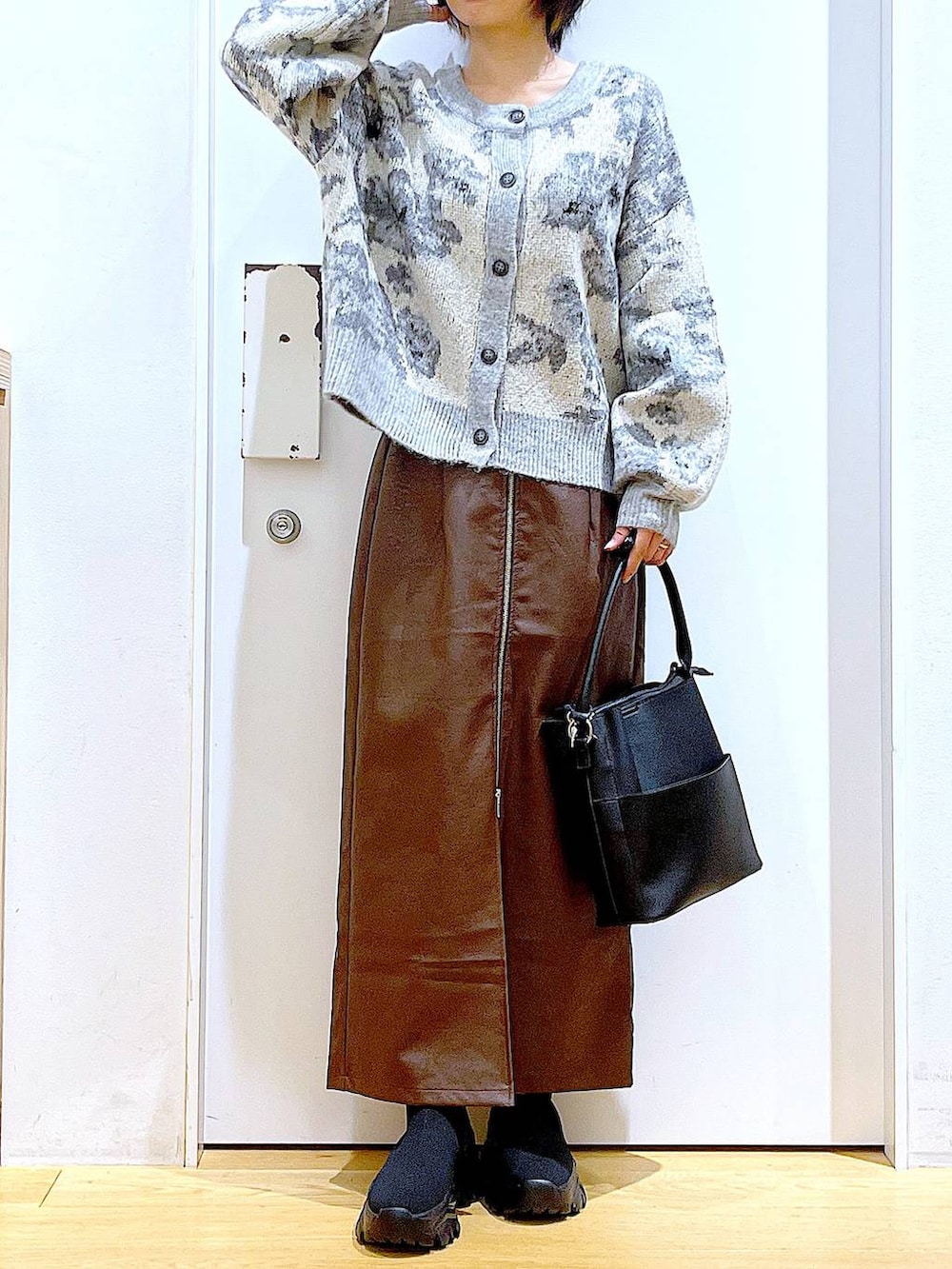 ブラウン系のスカート、ブラック系のショルダーバッグ、ブラック系のブーツを着用したレディースの冬コーディネートの6枚目の写真