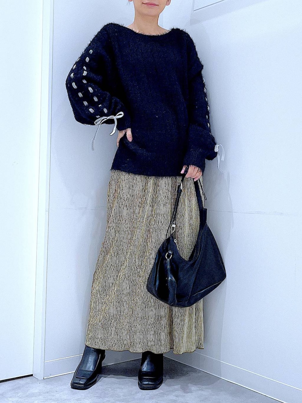 ブラック系のブーツ、ブラック系のニット/セーター、ブラック系のショルダーバッグを着用したレディースの冬コーディネートの6枚目の写真