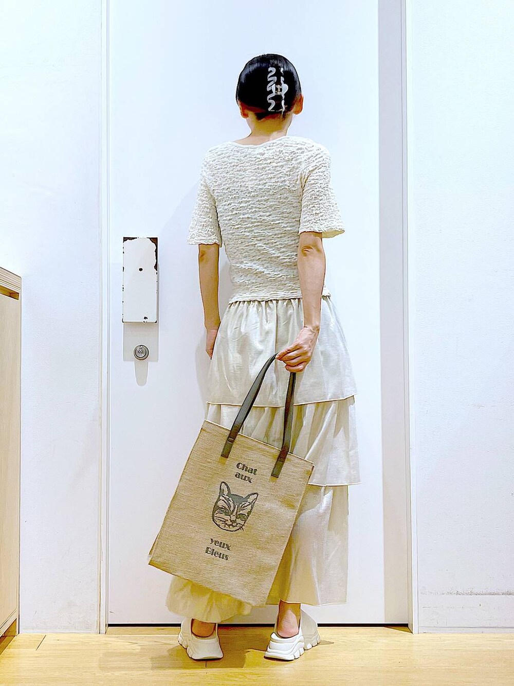 ホワイト系のサンダル、グレー系のトートバッグ、ゴールド系のスカートを着用したレディースの夏コーディネートの5枚目の写真