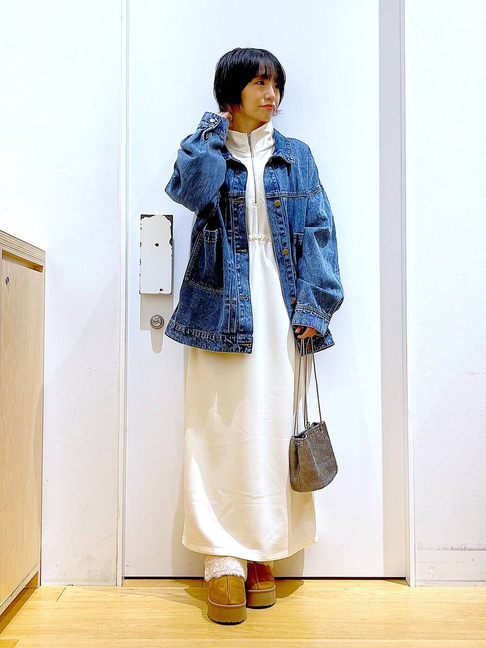 グレー系のショルダーバッグ、ベージュ系のワンピース、ベージュ系のスリッポンを着用したレディースの秋コーディネートの2枚目の写真