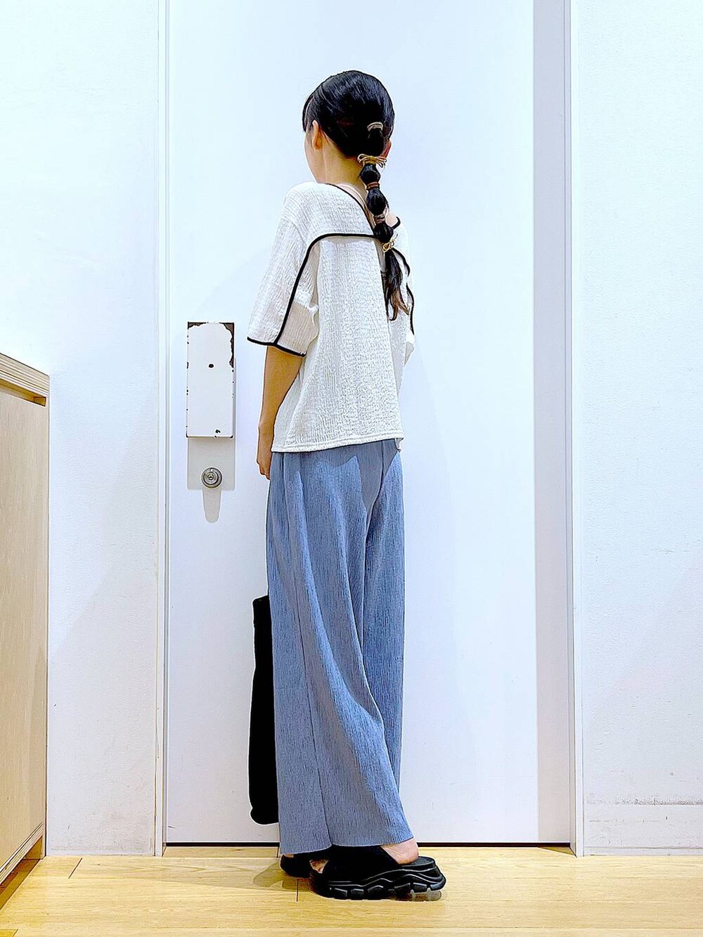 ブラック系のトートバッグ、ブラック系のサンダル、ホワイト系のTシャツ/カットソーを着用したレディースの夏コーディネートの3枚目の写真