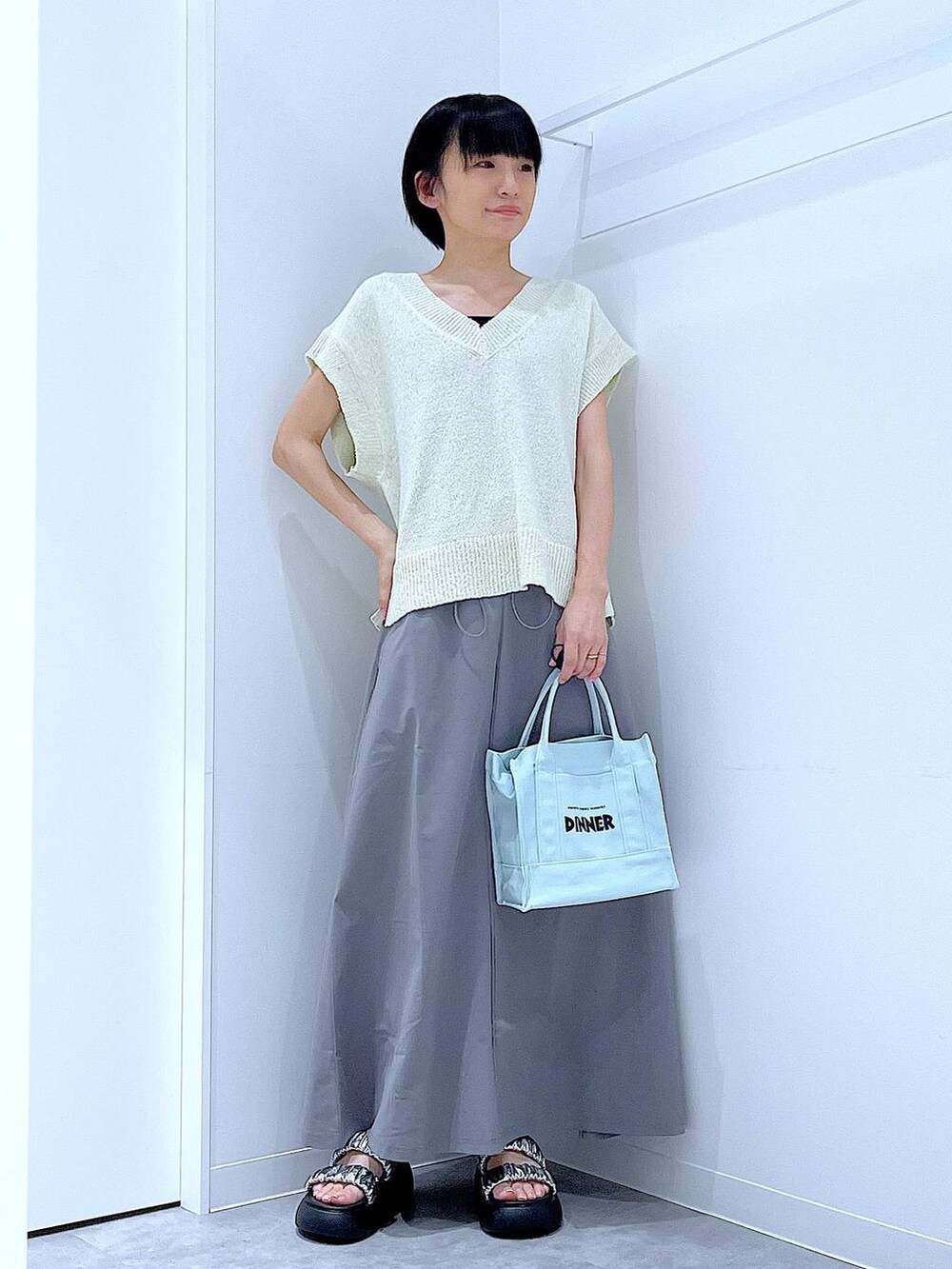 シルバー系のサンダル、グレー系のスカート、ホワイト系のベストを着用したレディースの夏コーディネートの2枚目の写真
