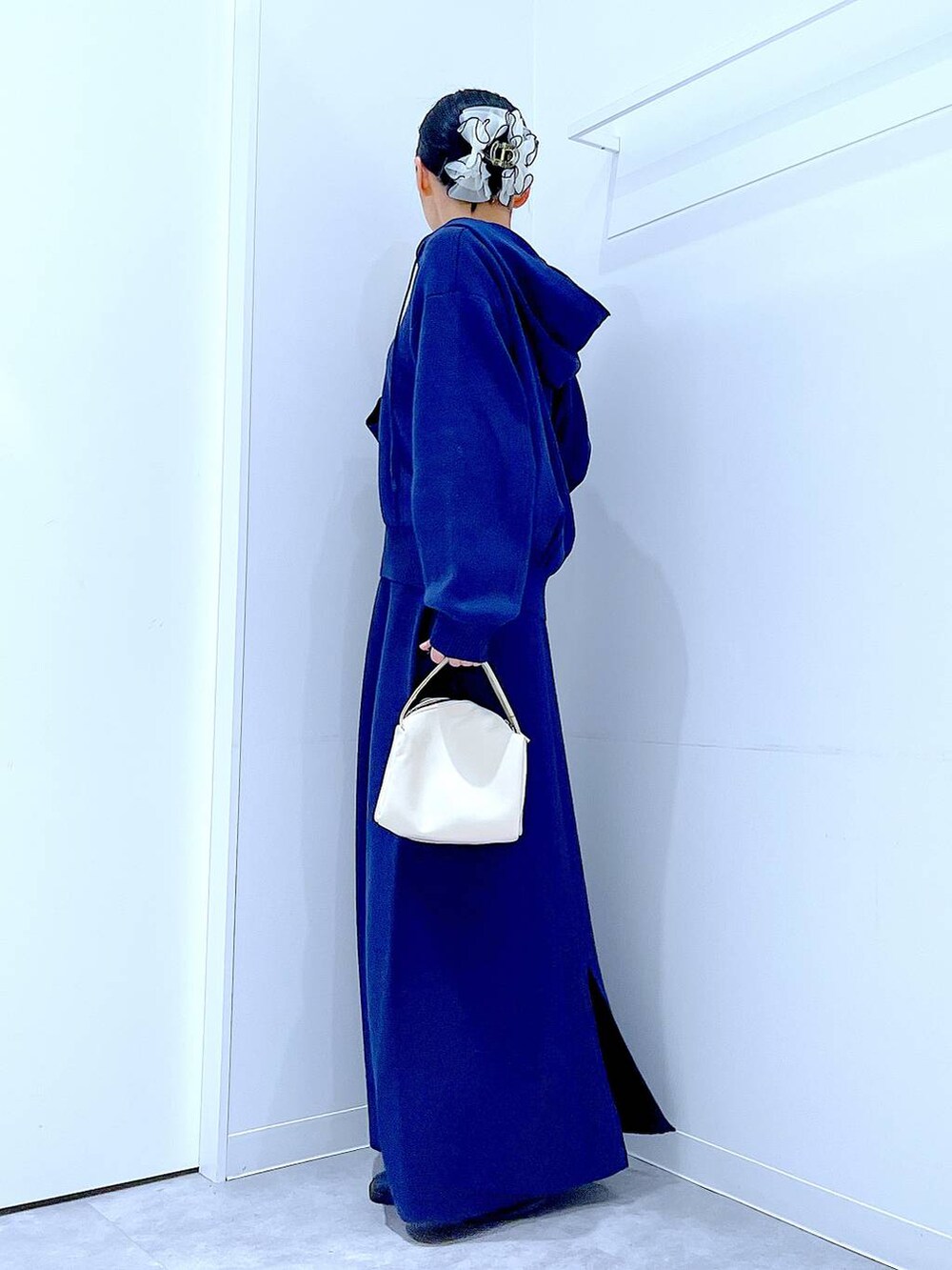 ブラック系のブーツ、ホワイト系のショルダーバッグ、ブルー系のスカートを着用したレディースの冬コーディネートの3枚目の写真