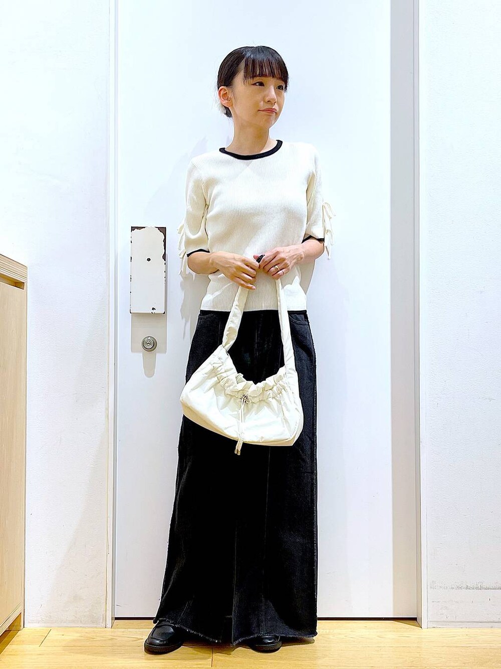 ホワイト系のハンドバッグ、ブラック系のローファー、ホワイト系のニット/セーターを着用したレディースの秋コーディネートの2枚目の写真