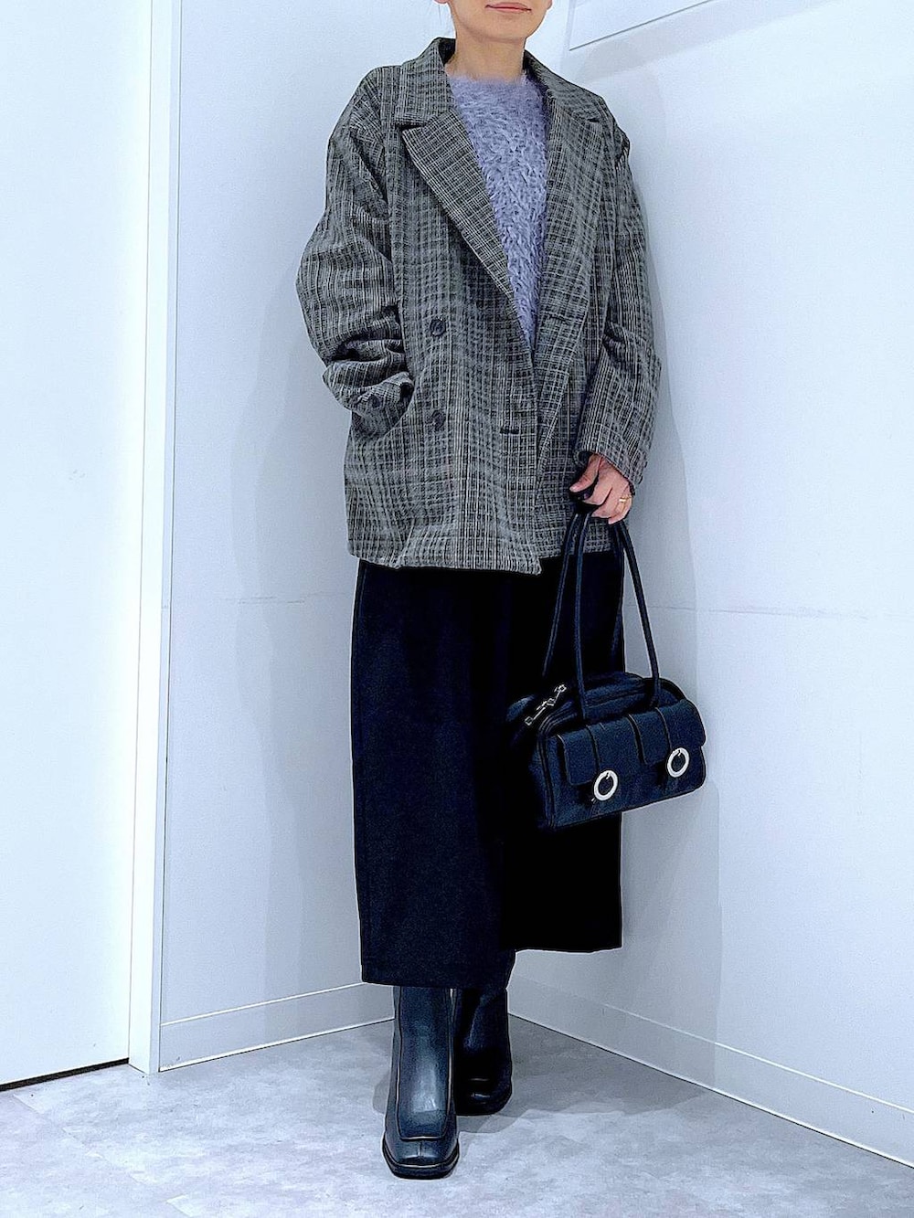 ブラック系のショルダーバッグ、ブラック系のスカート、ブラック系のブーツを着用したレディースの冬コーディネートの6枚目の写真