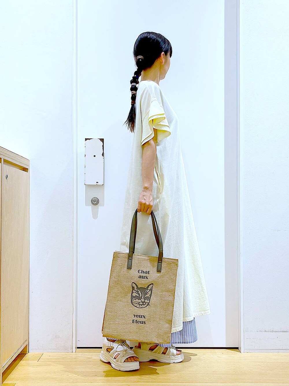 ホワイト系のサンダル、ベージュ系のワンピース、グレー系のトートバッグを着用したレディースの夏コーディネートの4枚目の写真