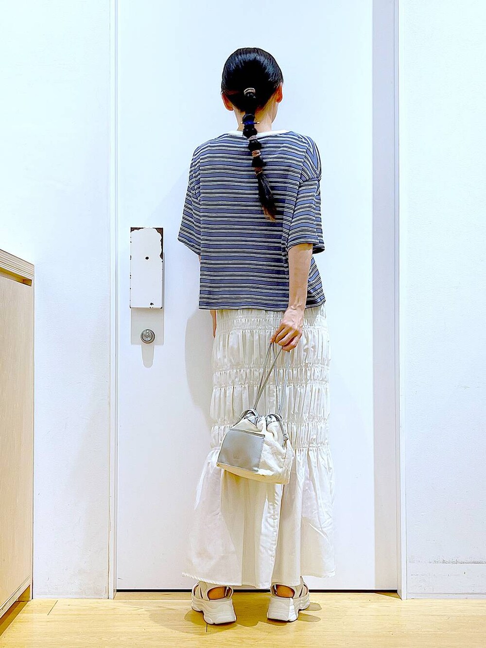 ホワイト系のショルダーバッグ、ホワイト系のサンダル、グレー系のTシャツ/カットソーを着用したレディースの夏コーディネートの5枚目の写真