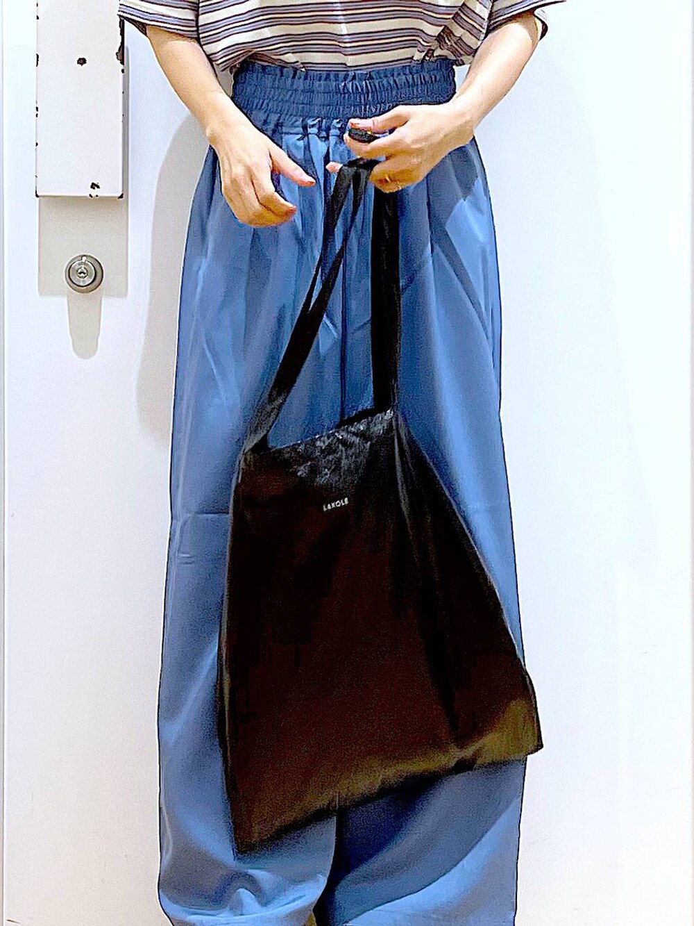 ブラック系のトートバッグ、ブラック系のサンダル、ベージュ系のTシャツ/カットソーを着用したレディースの夏コーディネートの9枚目の写真