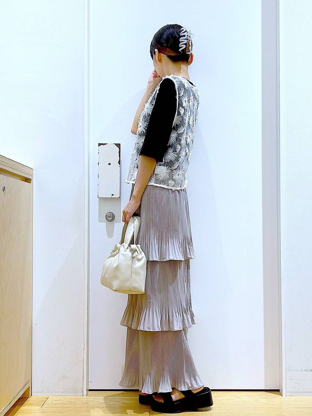 グレー系のスカート、ブラック系のサンダル、ホワイト系のショルダーバッグを着用したレディースの夏コーディネートの3枚目の写真