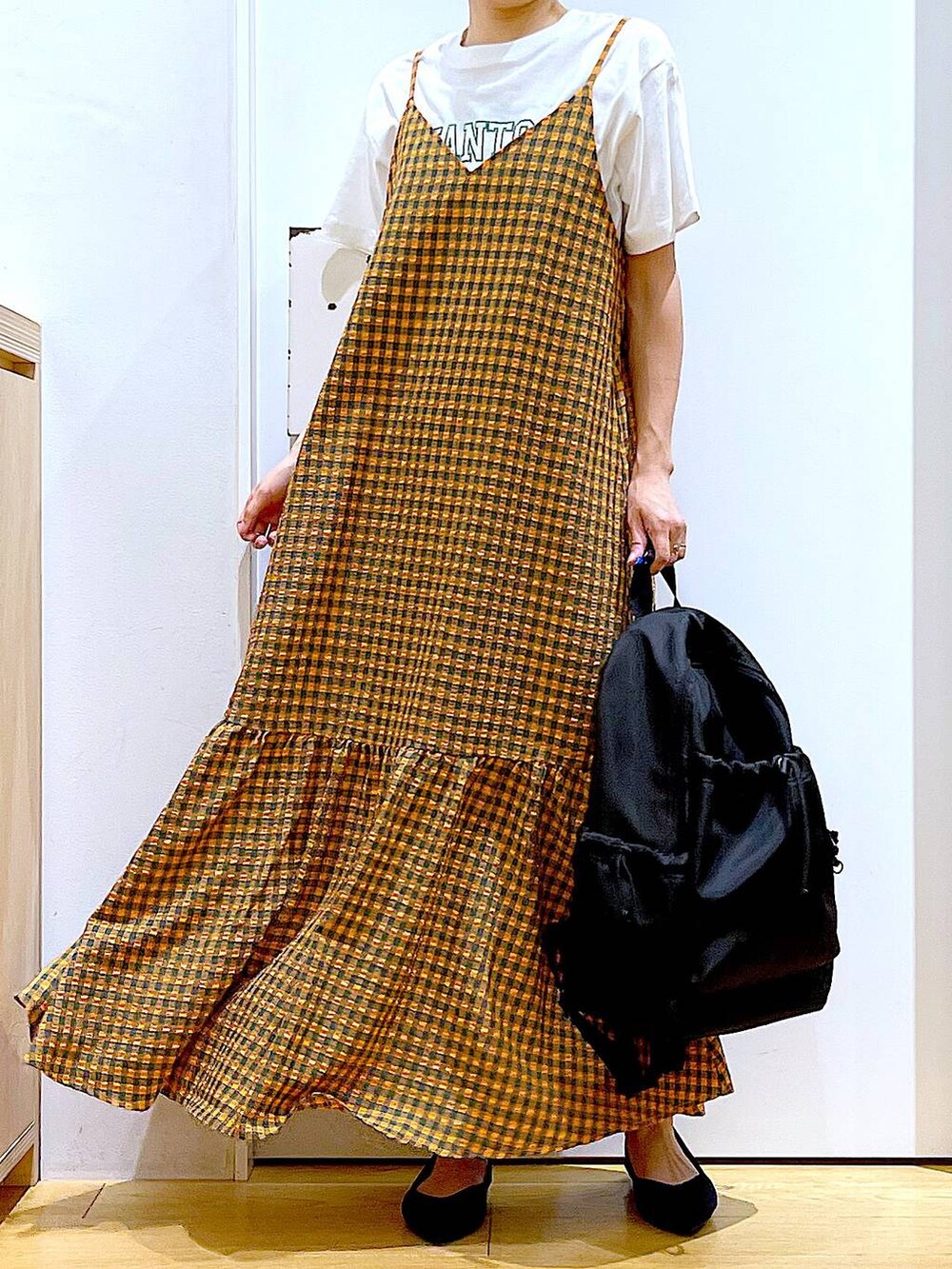 オレンジ系のワンピース、ブラック系のバックパック/リュック、ブラック系のパンプスを着用したレディースの春コーディネートの6枚目の写真