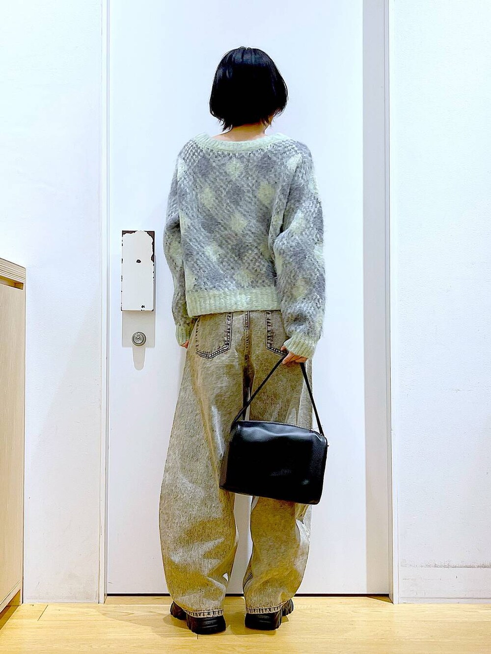 ブラック系のショルダーバッグ、ブラック系のブーツ、ベージュ系のデニムパンツを着用したレディースの冬コーディネートの5枚目の写真