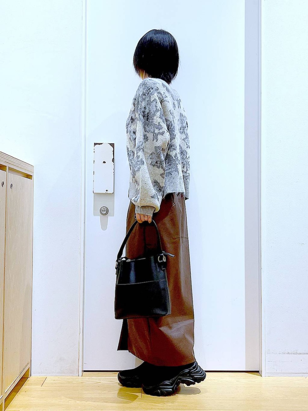 ブラウン系のスカート、ブラック系のショルダーバッグ、ブラック系のブーツを着用したレディースの冬コーディネートの3枚目の写真