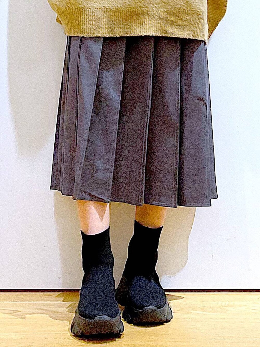 ホワイト系のハンドバッグ、ブラック系のブーツ、グレー系のスカートを着用したレディースの冬コーディネートの8枚目の写真