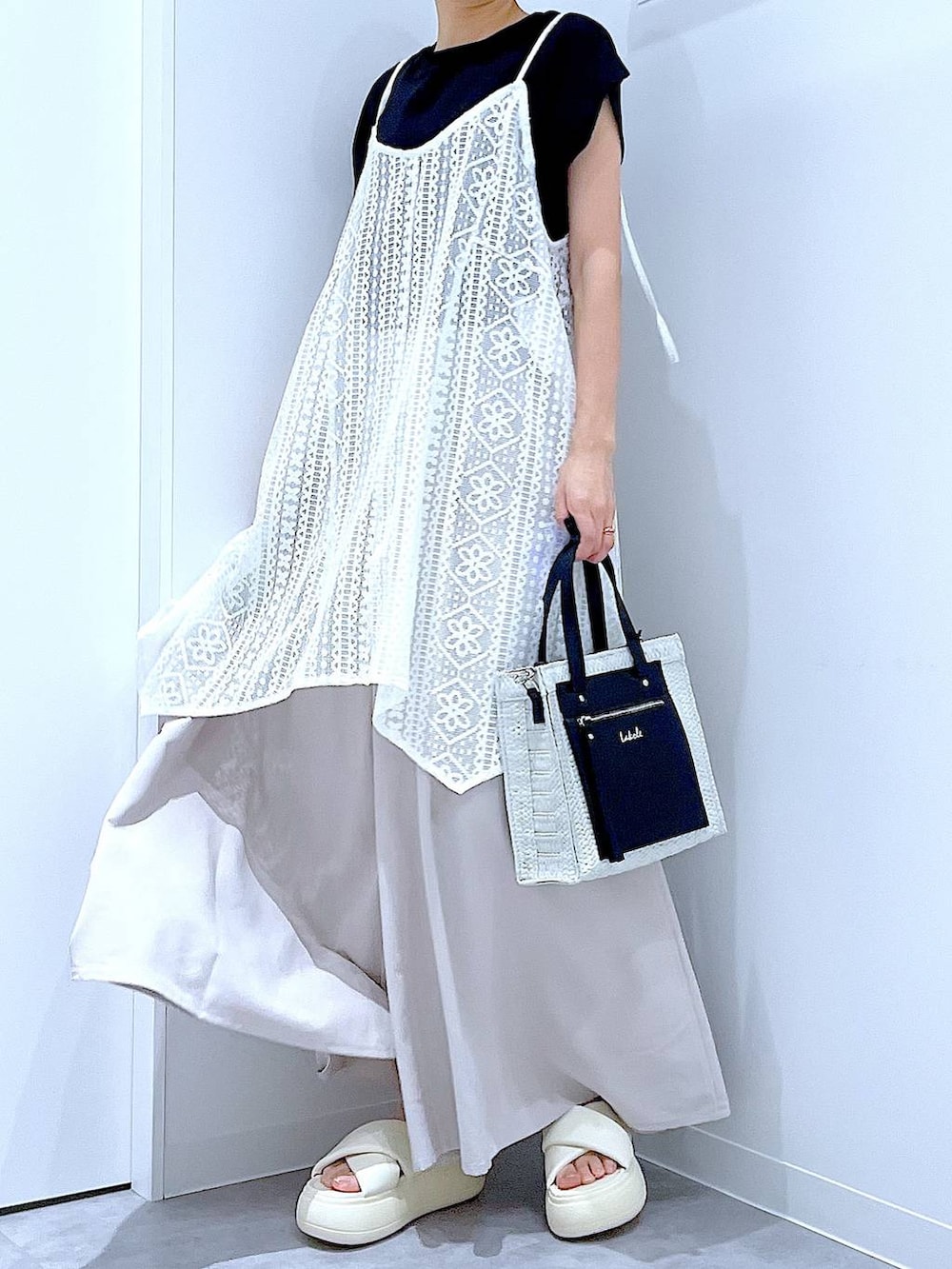ホワイト系のショルダーバッグ、ホワイト系のサンダル、ブラック系のTシャツ/カットソーを着用したレディースの夏コーディネートの6枚目の写真
