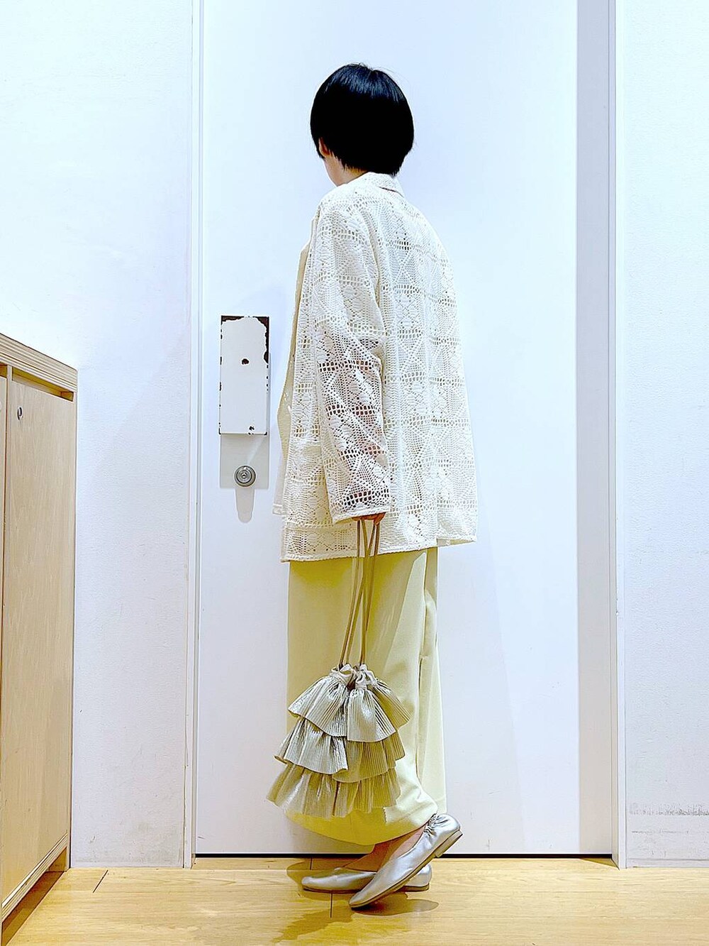 シルバー系のパンプス、ベージュ系のショルダーバッグ、イエロー系のスカートを着用したレディースの春コーディネートの3枚目の写真