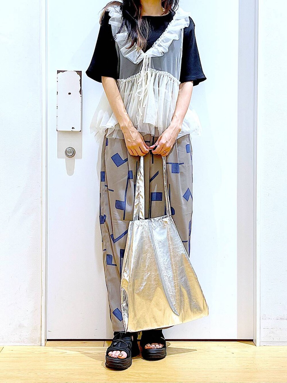 シルバー系のトートバッグ、グレー系のその他パンツ、ブラック系のサンダルを着用したレディースの夏コーディネートの6枚目の写真