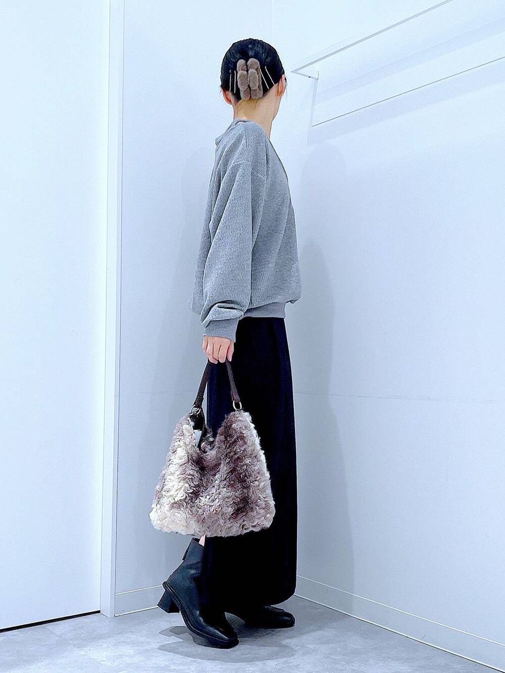 ブラック系のスカート、ブラック系のブーツ、ブラウン系のショルダーバッグを着用したレディースの冬コーディネートの4枚目の写真