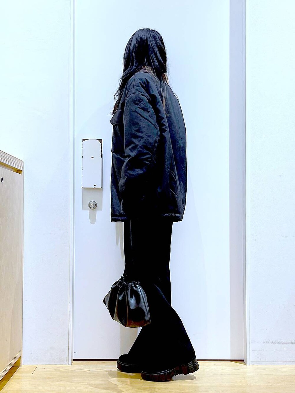 ブラック系のブルゾン、ブラック系のショルダーバッグ、ブラック系のブーツを着用したレディースの冬コーディネートの3枚目の写真