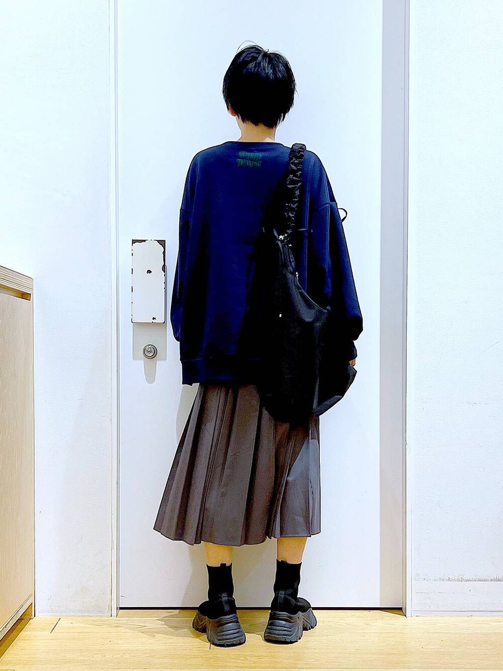 ブラック系のショルダーバッグ、ブラック系のブーツ、グレー系のスカートを着用したレディースの冬コーディネートの5枚目の写真