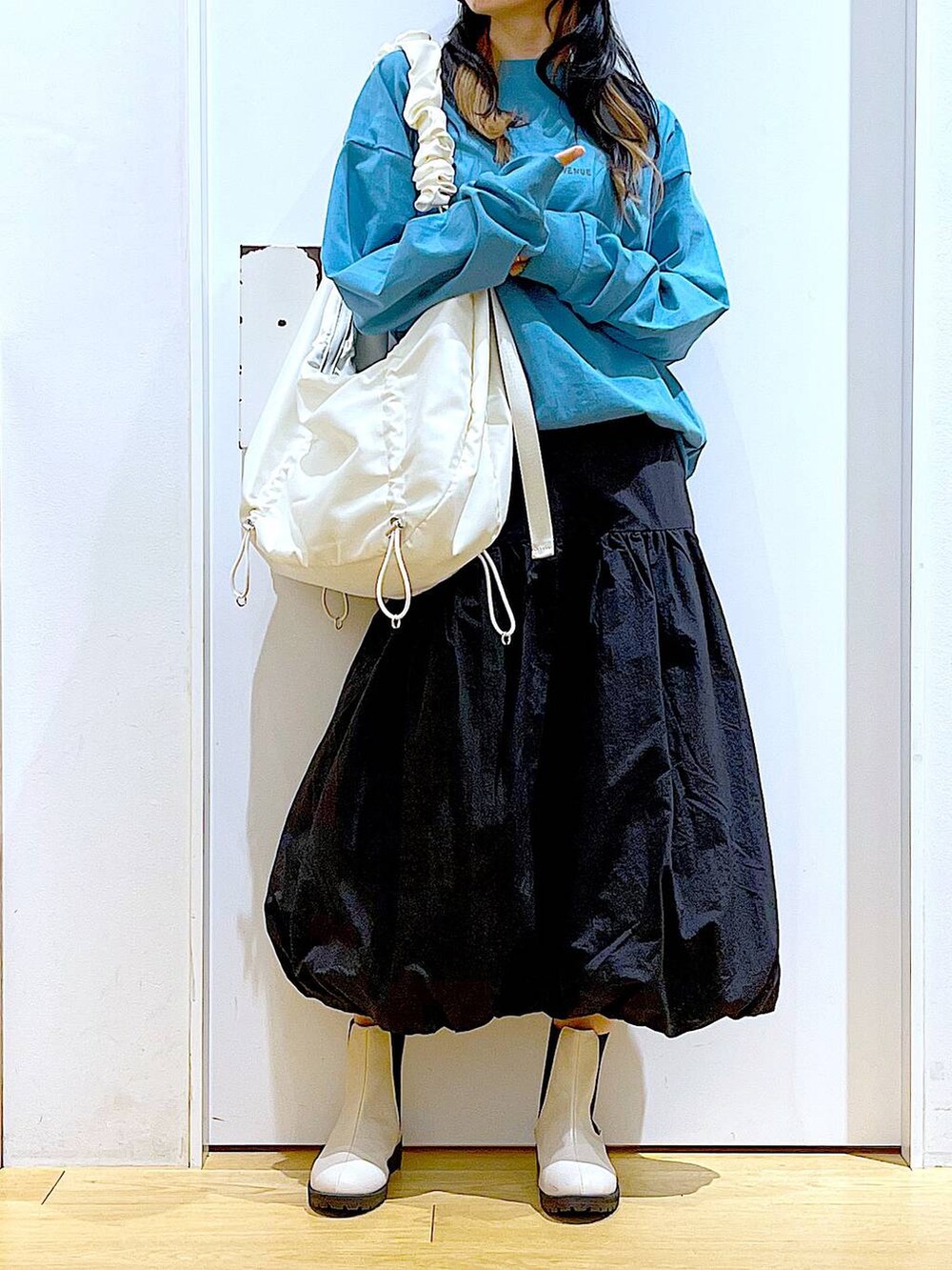 グリーン系のTシャツ/カットソー、ベージュ系のブーツ、ホワイト系のショルダーバッグを着用したレディースの春コーディネートの6枚目の写真