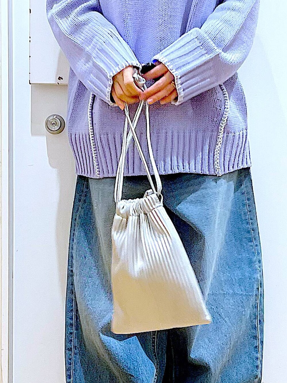 シルバー系のショルダーバッグ、ベージュ系のブーツ、ブルー系のデニムパンツを着用したレディースの冬コーディネートの9枚目の写真