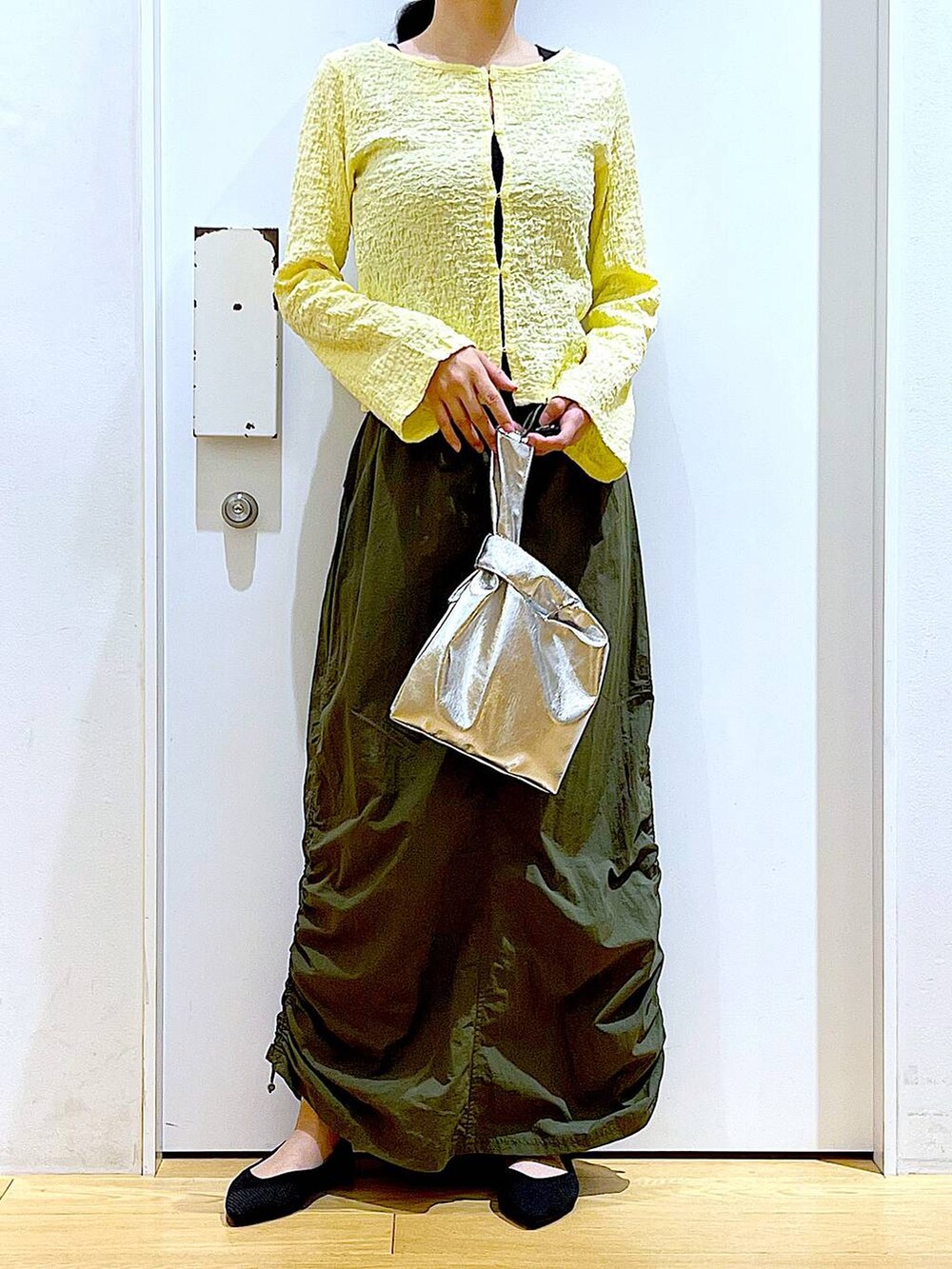 シルバー系のショルダーバッグ、グリーン系のスカート、ブラック系のパンプスを着用したレディースの春コーディネートの6枚目の写真