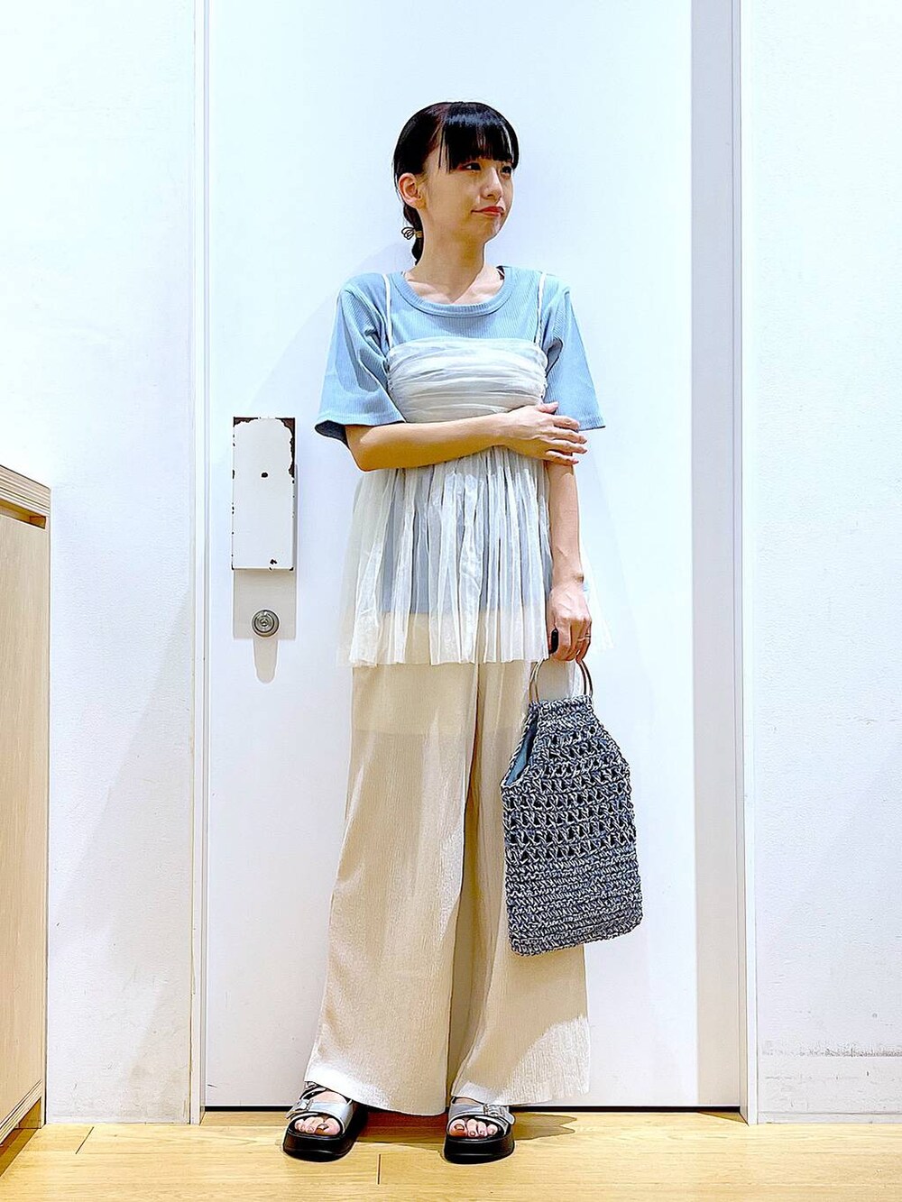 ホワイト系のキャミソール、シルバー系のサンダル、ブルー系のハンドバッグを着用したレディースの夏コーディネートの2枚目の写真