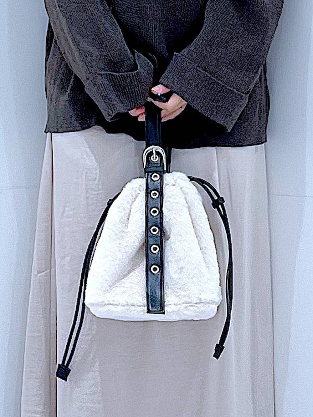 ホワイト系のハンドバッグ、ベージュ系のスカート、ブラック系のブーツを着用したレディースの秋コーディネートの9枚目の写真