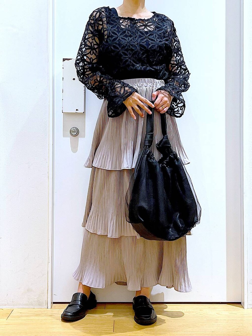 グレー系のスカート、ブラック系のトートバッグ、ブラック系のローファーを着用したレディースの秋コーディネートの6枚目の写真